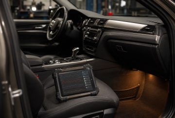 Diagnostický tablet s priebehmi zo snímačov na sedadle v otvorenom aute v servisnej dielni